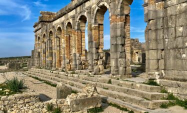 Explore the intricate remains of ancient Roman ruins basking in sunlight under a vivid blue sky.