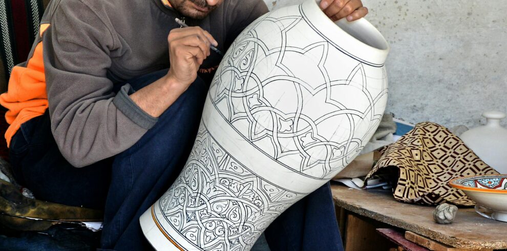Artisan in Fès, Morocco intricately designs a large clay vase, showcasing traditional craftsmanship.
