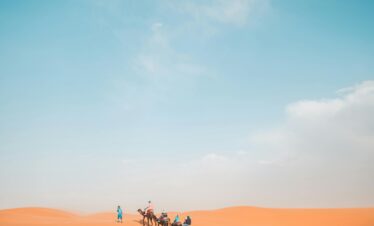 A camel caravan crosses the vast dunes in Al Wahat Al Dakhla Desert, Egypt.